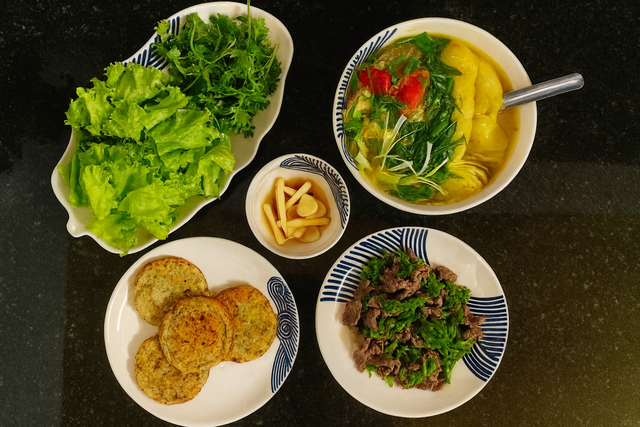 Món ăn ngon trong mâm cơm này có: Chả chiên + thịt bò xào hoa điên điển + rau sống + canh chua.