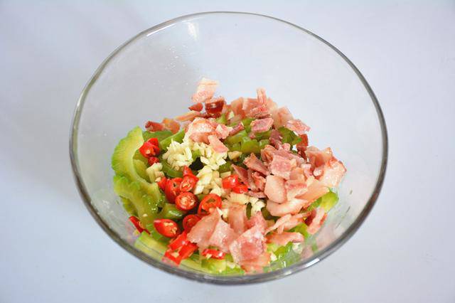 Trộn khổ qua với nước tương, dầu mè, chút giấm, đường, tỏi băm, ớt hiểm và thịt xông khói.